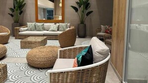 Un espace de détente moderne, avec des meubles en osier, un grand miroir et des plantes en pot.
