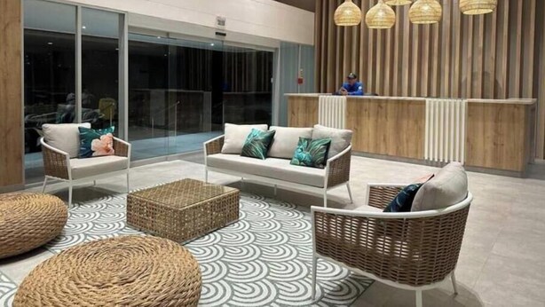 Un hall d’entrée moderne avec un comptoir d’accueil, des meubles en osier et un revêtement de sol à motifs.