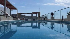 Une piscine d’un bleu éclatant, dotée d’un espace abrité, de plantes en pot et offrant une vue sur des collines lointaines.