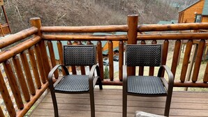 Una terraza de madera con dos sillas y baranda de madera.