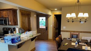 Una cocina con armarios de madera, encimera de granito y comedor con mesa y sillas.