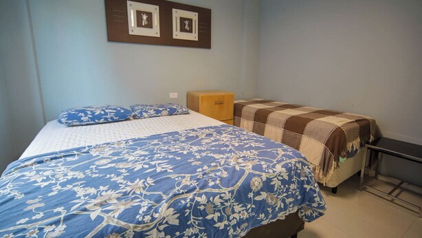 A bedroom with a bed, a bedside table, a dresser, and a television.