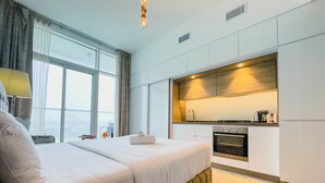 Ein modernes Hotelzimmer mit einem großen Bett, einer integrierten Küche und Blick auf die Stadt.