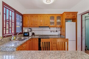 A kitchen with wooden cabinets, granite countertops, a built-in dishwasher, and a refrigerator.