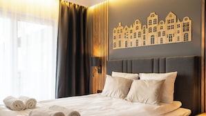 A neatly made bed with rolled towels, a headboard, and a wall-mounted light fixture. - RentPlanet - Sienkiewicza Residence (Wrocław)