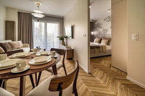 Quarto de hotel moderno com área de jantar, sofá e cama.
