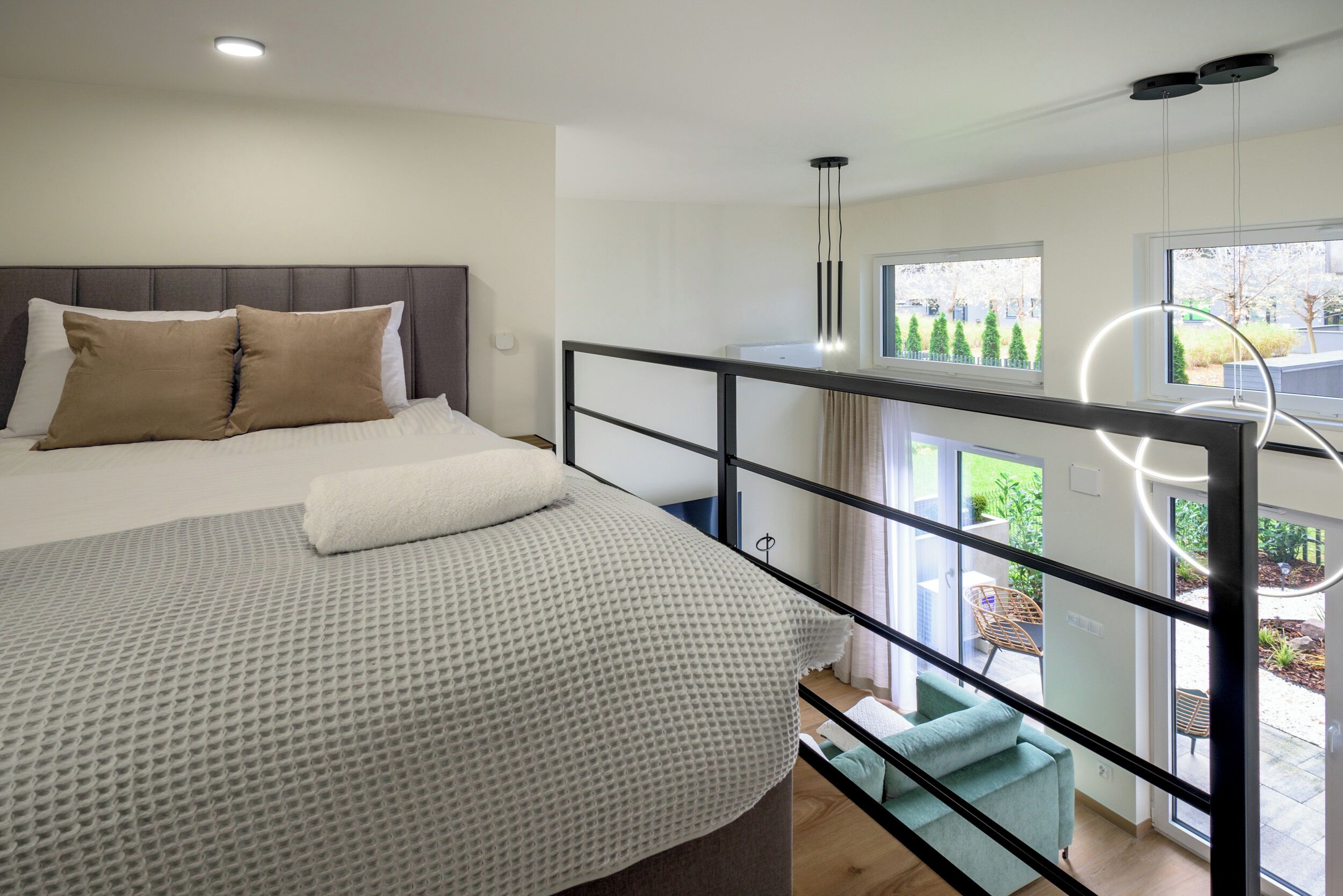 Una camera da letto moderna con un letto, un balcone con ringhiera e vista sull'esterno.