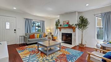 A living room with a fireplace, a sofa, a coffee table, and a patterned rug.