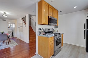 A kitchen with wooden cabinets, a stainless steel stove, and a microwave.