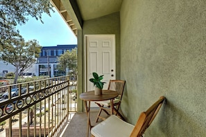 A balcony with a table and chairs, a potted plant, and a view of a building in the background.