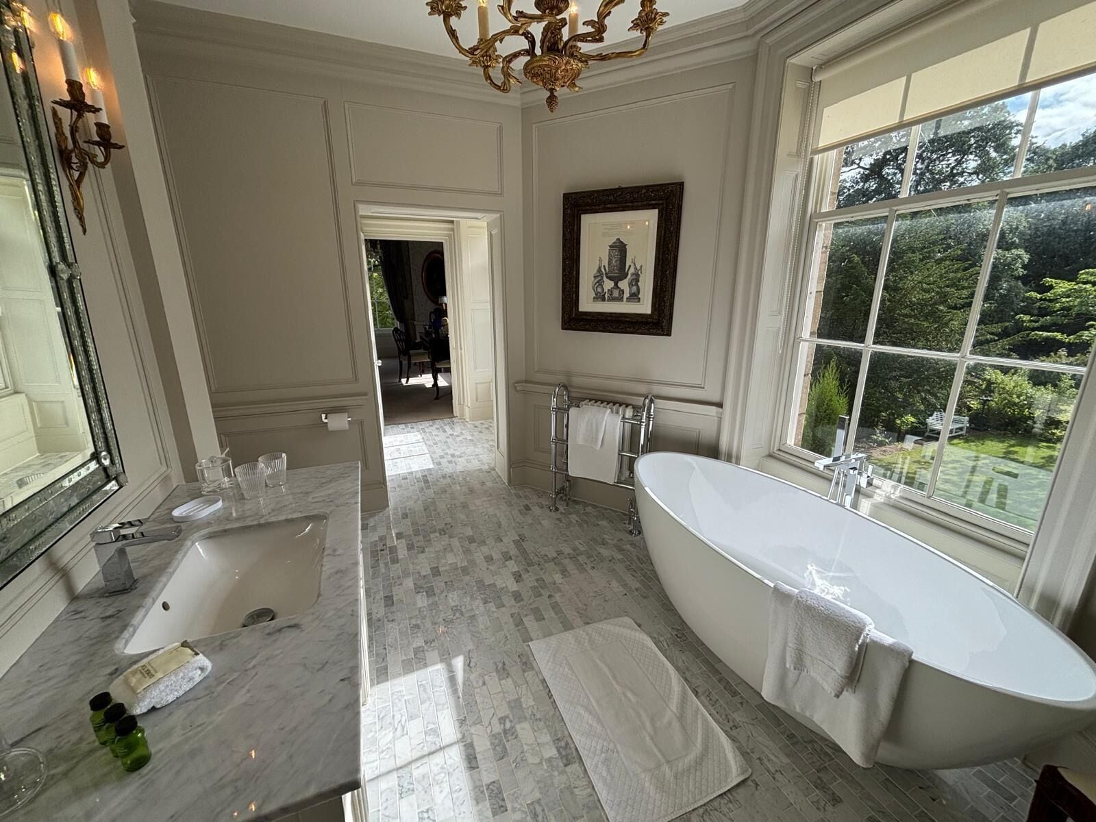 Un baño amplio con una bañera independiente, un espejo grande y un ventanal con vistas al exterior.