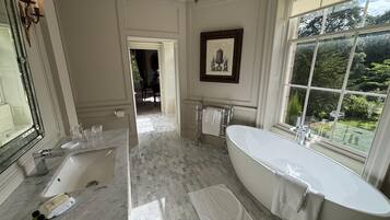 Un baño amplio con una bañera independiente, un espejo grande y un ventanal con vistas al exterior.