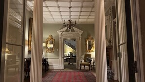 A grand hallway with white columns, a red patterned carpet, and two ornate gold-framed mirrors. - Park Hall Manor (High Peak)