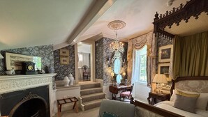 A traditional room with a fireplace, a sofa, a table with a book, a mirror, and a chandelier. - Park Hall Manor (High Peak)