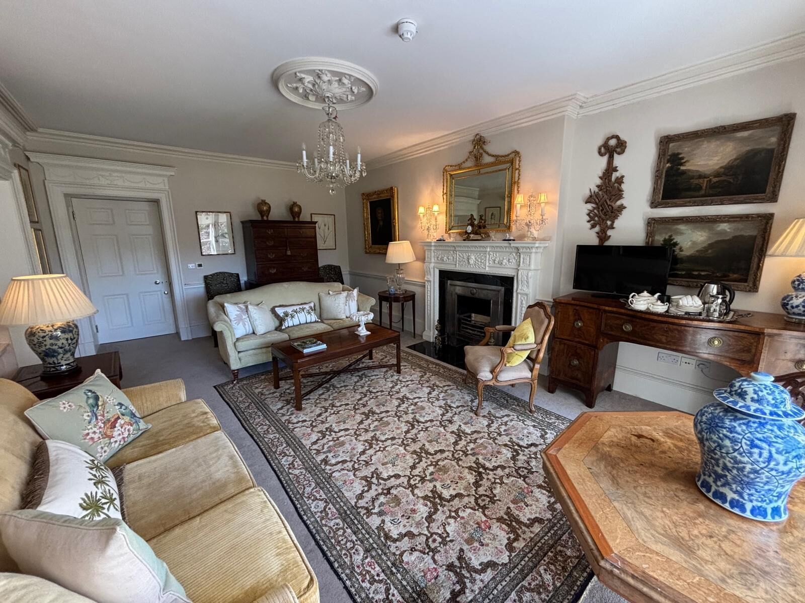 Un salon traditionnel avec une cheminée, un canapé, une table basse et des objets décoratifs.