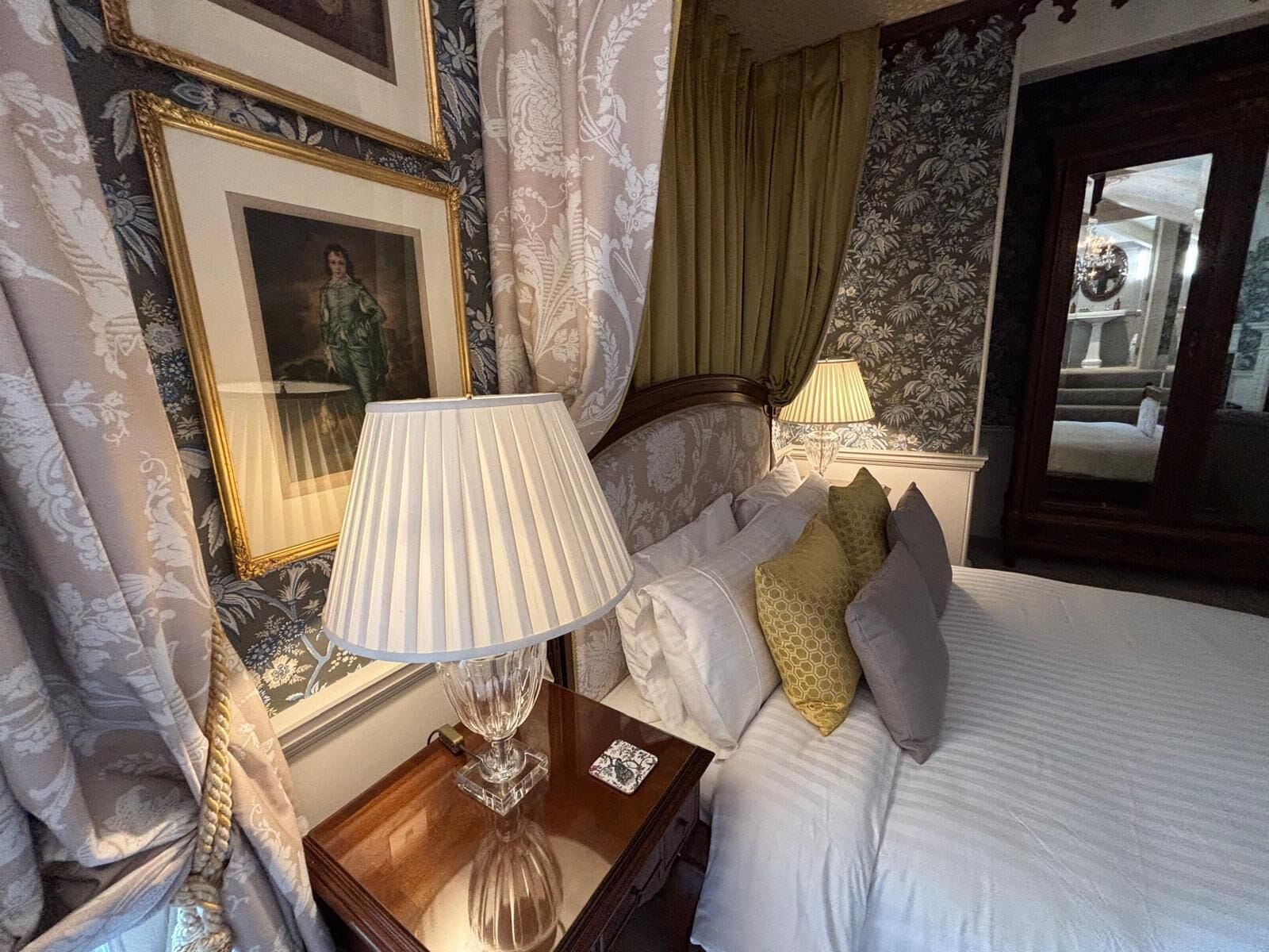 Una habitación de hotel con cama, mesita de noche con lámpara y un cuadro en la pared.