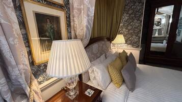 Una habitación de hotel con cama, mesita de noche con lámpara y un cuadro en la pared.