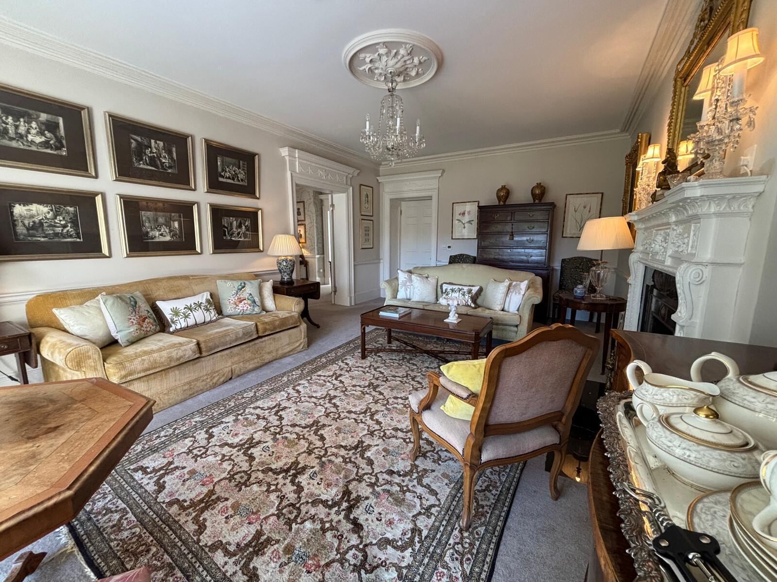A traditional living room with a sofa, armchairs, a coffee table, and a fireplace.