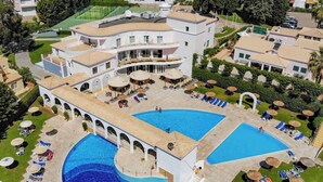 Een resort met een groot centraal zwembad, meerdere kleinere zwembaden en buitengelegen zitgedeeltes.