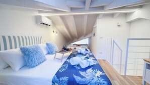Een slaapkamer met een bed, kussens, een tafel met een dienblad eten en handdoeken.