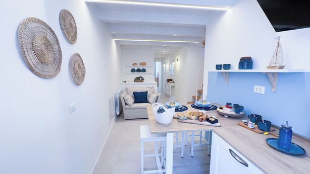 Een moderne keuken met een houten aanrecht, witte kastjes en een eethoek met een gedekte tafel.