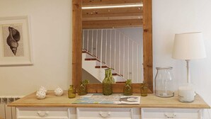 Een houten dressoir met een spiegel, decoratieve vazen en een kaars.