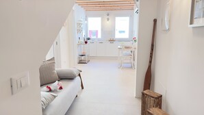 A bright, modern kitchen with white cabinets, a dining table, and a staircase leading to an upper level. - Calle Piva, 788 by Ca-Sa Check (Chioggia)