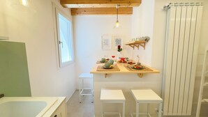 A compact kitchen with a wooden ceiling, a small dining table set with dishes, and a white radiator. - Calle Piva, 788 by Ca-Sa Check (Chioggia)