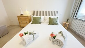 Un lit bien fait, avec des oreillers, une table de chevet avec une lampe et un petit tabouret.