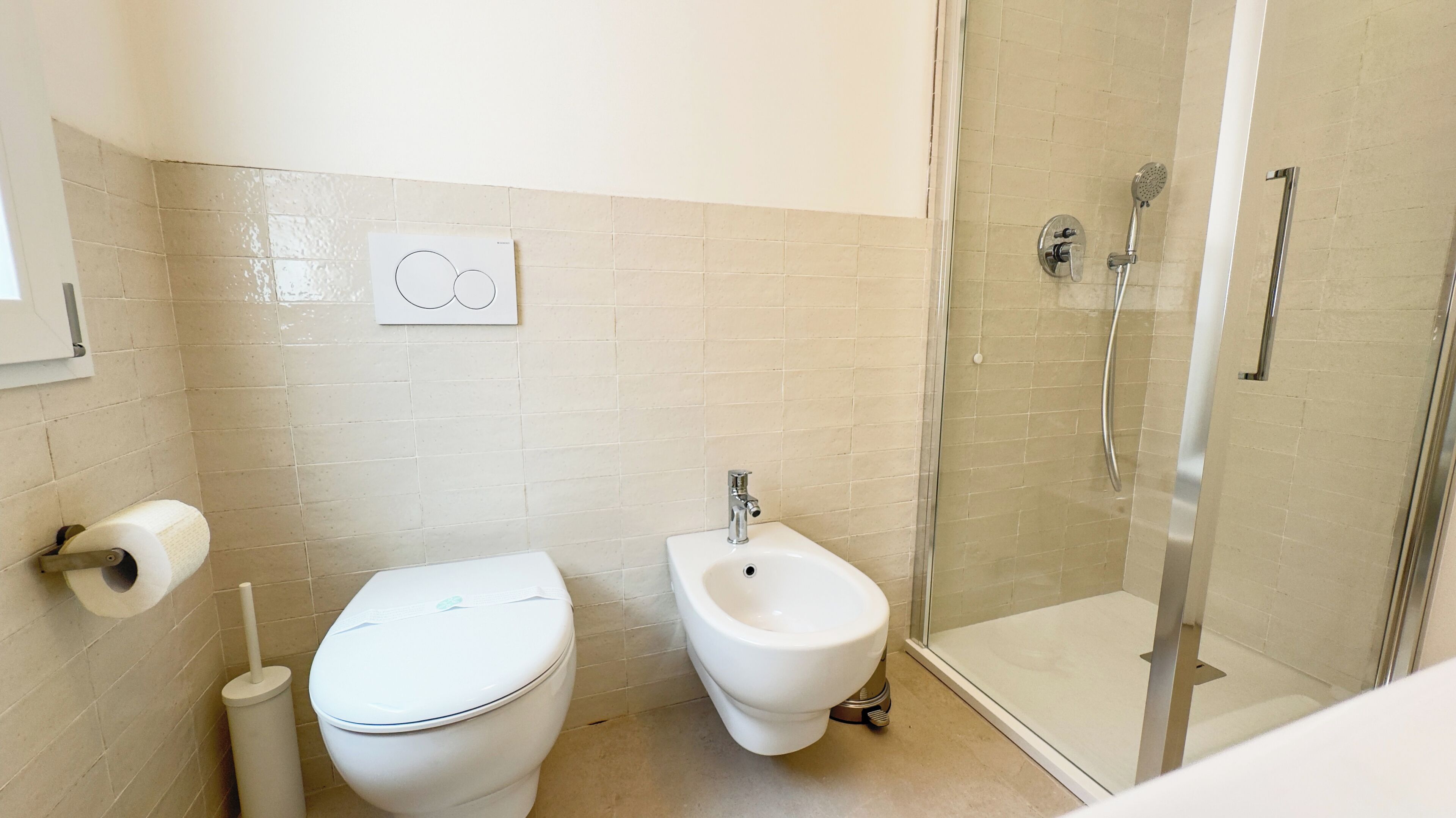 Une salle de bain équipée de toilettes, d’un bidet et d’une douche à parois de verre.