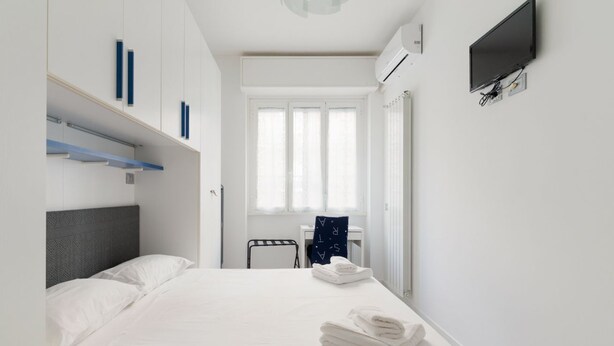 A hotel room with a bed, a desk, a chair, and a TV.
