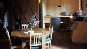 Un interior de madera con una mesa de comedor, sillas y una zona de cocina.