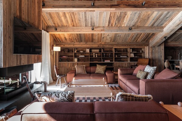 Una sala de estar acogedora con chimenea, sofás de cuero, una mesa de centro y una estantería llena de libros y objetos decorativos.