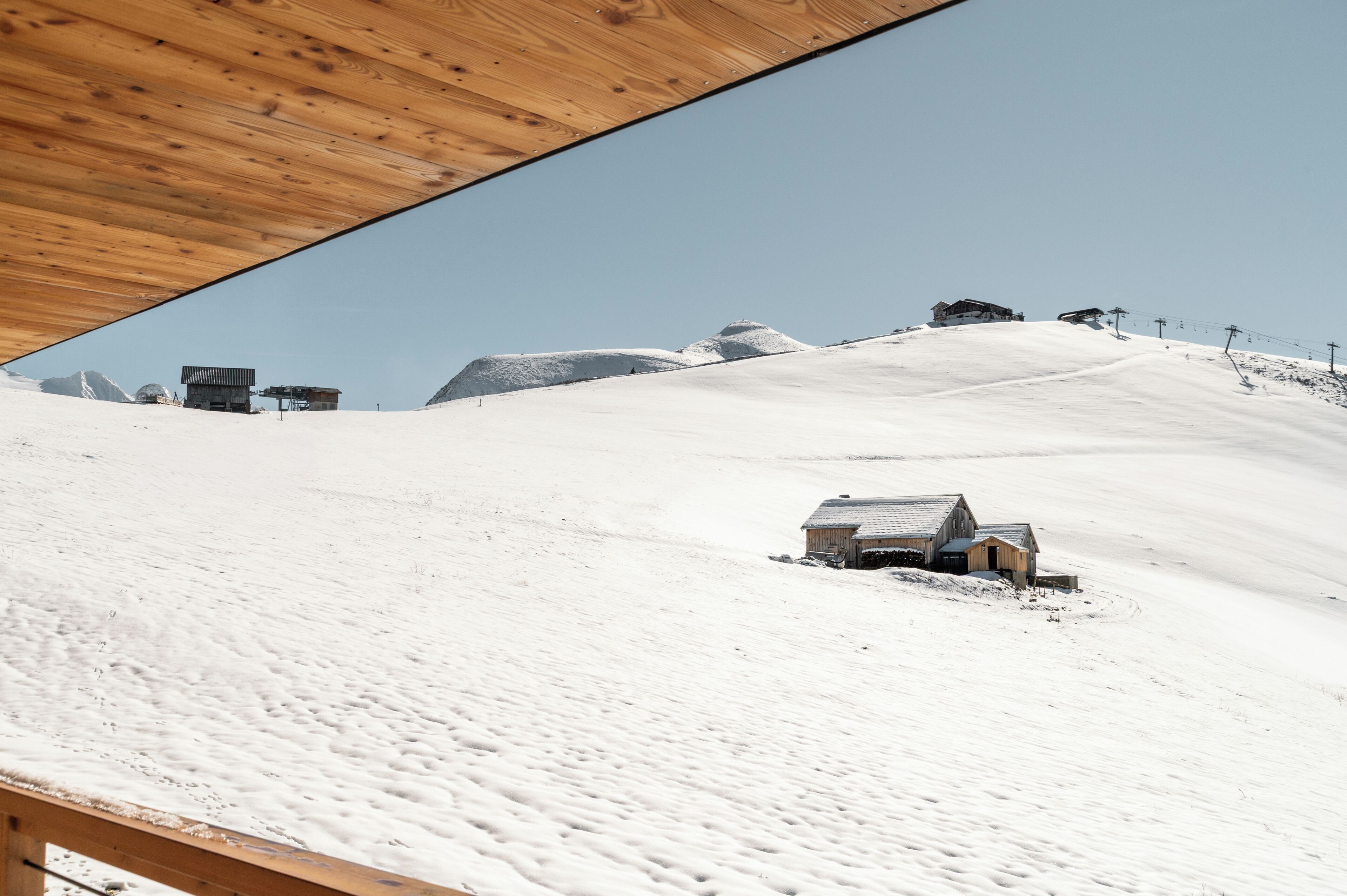 A snow-covered mountain with a wooden structure at the top and a small building at the base.