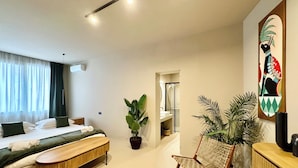 A modern hotel room with a bed, a bench, a potted plant, a wooden dresser, and a bathroom visible through an open door. - CARBONE XXI (Catania)