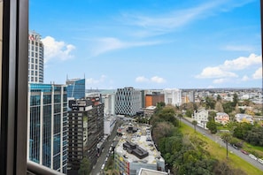 A cityscape with modern buildings, a parking lot, and a clear sky.