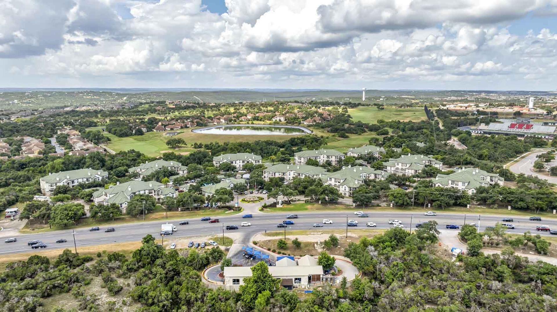 A residential area with houses, a roundabout, and a large body of water in the background.