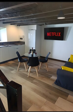 A modern living space with a dining area, kitchen, and a large flat-screen TV mounted on the wall. - Vacation at 'Casa Miranda 3' with Private Terrace, Wi-Fi and Air Conditioning (Igueste de Candelaria)