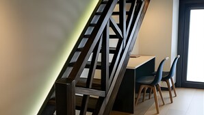 Un escalier moderne avec des rampes en bois et un bureau avec des chaises, le tout dans une pièce bien éclairée.