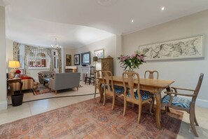 A spacious living area with a dining table, chairs, and a patterned rug.