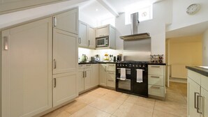 A modern kitchen with white cabinets, a black stove, and a microwave.