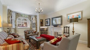 A living room with a sofa, armchair, and ottoman, a fireplace, and a television.