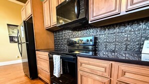 A kitchen with wooden cabinets, a black refrigerator, a black stove, and a patterned backsplash. - Stunning 2 bedroom in town, close to Shawnee National Forest (Jonesboro)