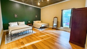 A bedroom with two beds, a wooden floor, a green wall, a window with a view, and a ceiling fan. - Stunning 2 bedroom in town, close to Shawnee National Forest (Jonesboro)