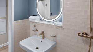 A bathroom with a white sink, a round mirror, and a towel rack. - City view apartment 9 Schlehe (Lüneburg)