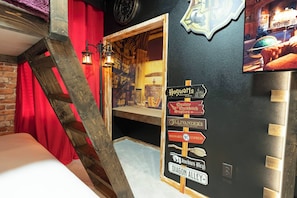 Una habitación temática con una escalera de madera, un panel con varios letreros alusivos a Hogwarts y una estantería.
