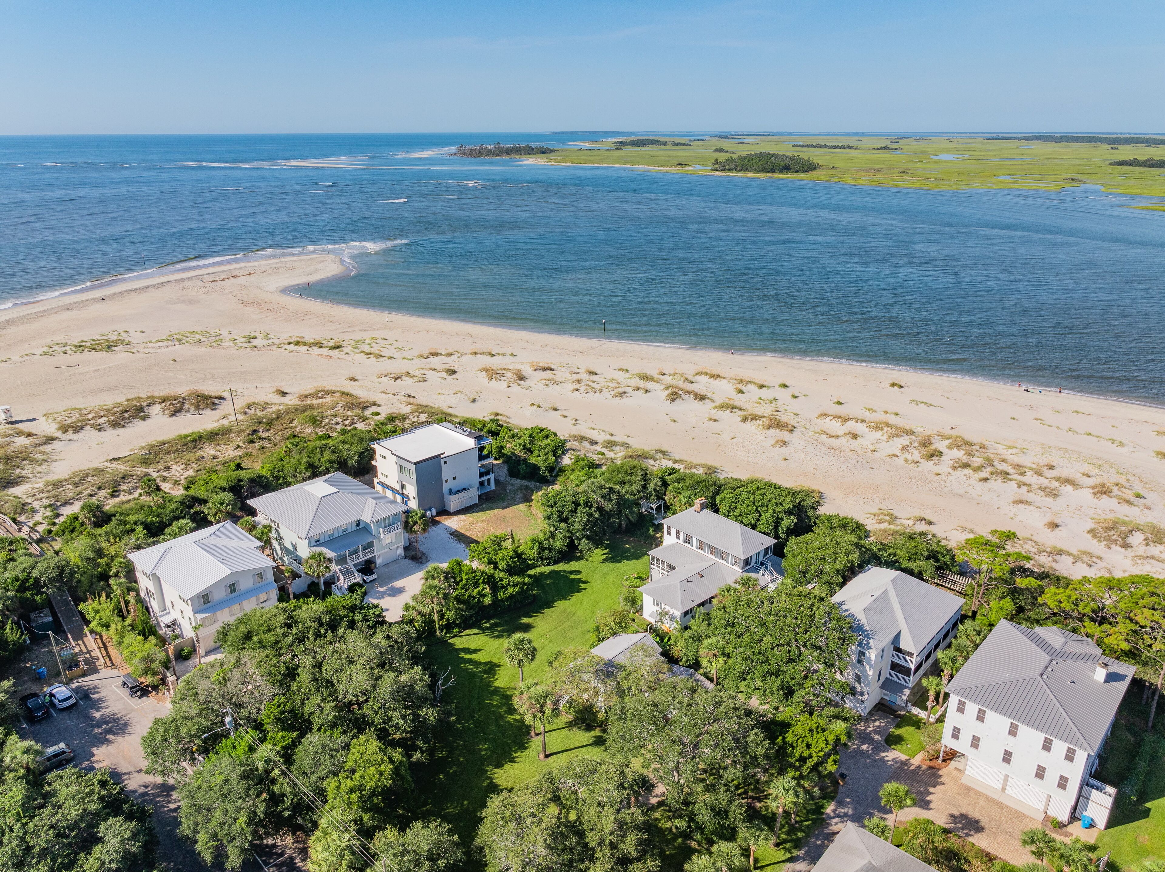 Et kystnære boligområde med flere huse, en sandstrand og udsigt over havet.
