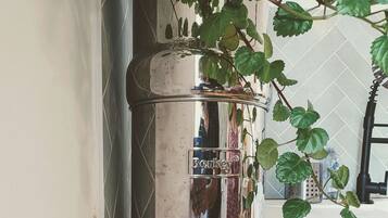 Een keuken met een Berkey waterfilter op een houten plank, een spoelbak en een raam met uitzicht op het exterieur.