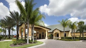 A hotel with a central courtyard, palm trees, and a tiled walkway.