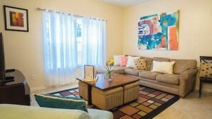 A living room with a sofa, coffee table, and a painting on the wall.